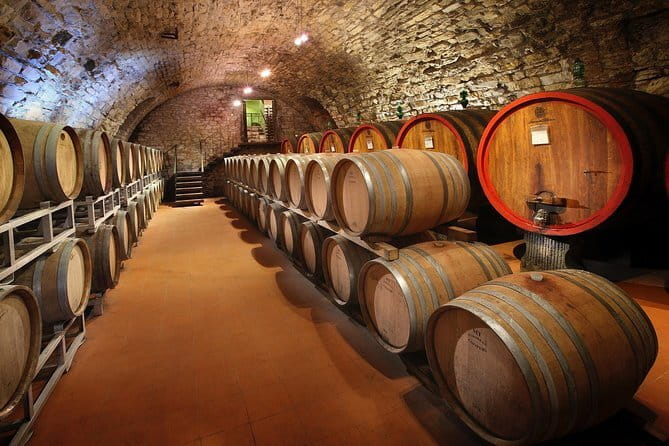 Oak barrels in a lit stone cellar tunnel in Tuscany